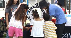Whole Communities–Whole Health Research Coordinator Sarah Smith (in hat), with children at Del Valle Day, June 2024.
