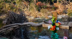 A cross at a memorial in Guadalupe Park is seen near downed trees in the Guadalupe River from the July 4 floods, Friday, July 25, 2025, in Kerrville, Texas. While we cannot erase tragedies, we can use our knowledge and research to improve preparedness, warnings and response, writes David R. Maidment. Photo by Elías Valverde II, Dallas Morning News staff photographer